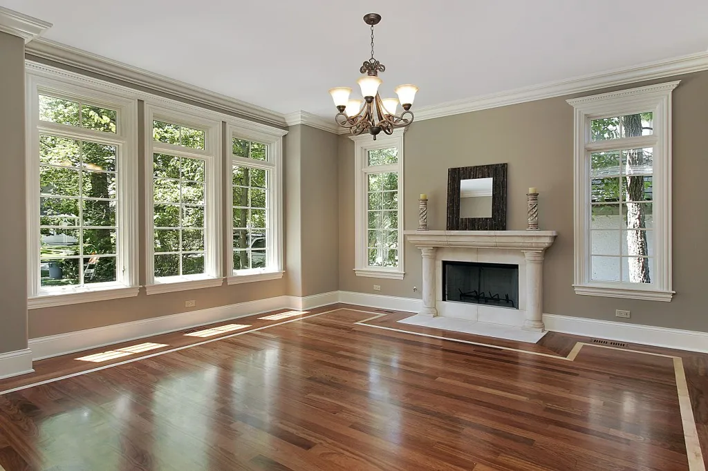 Living room with taupe walls, white window trim and fireplace surround repainted, hardwood floors
