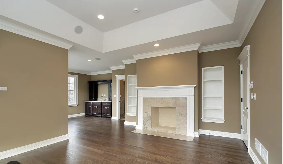 Living room with warm tan walls, white crown molding, fireplace and built-in bookshelves repainted