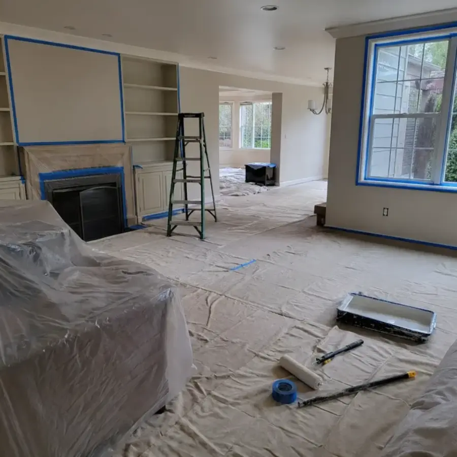 Living room with furniture and floors fully protected with drop cloths before interior painting