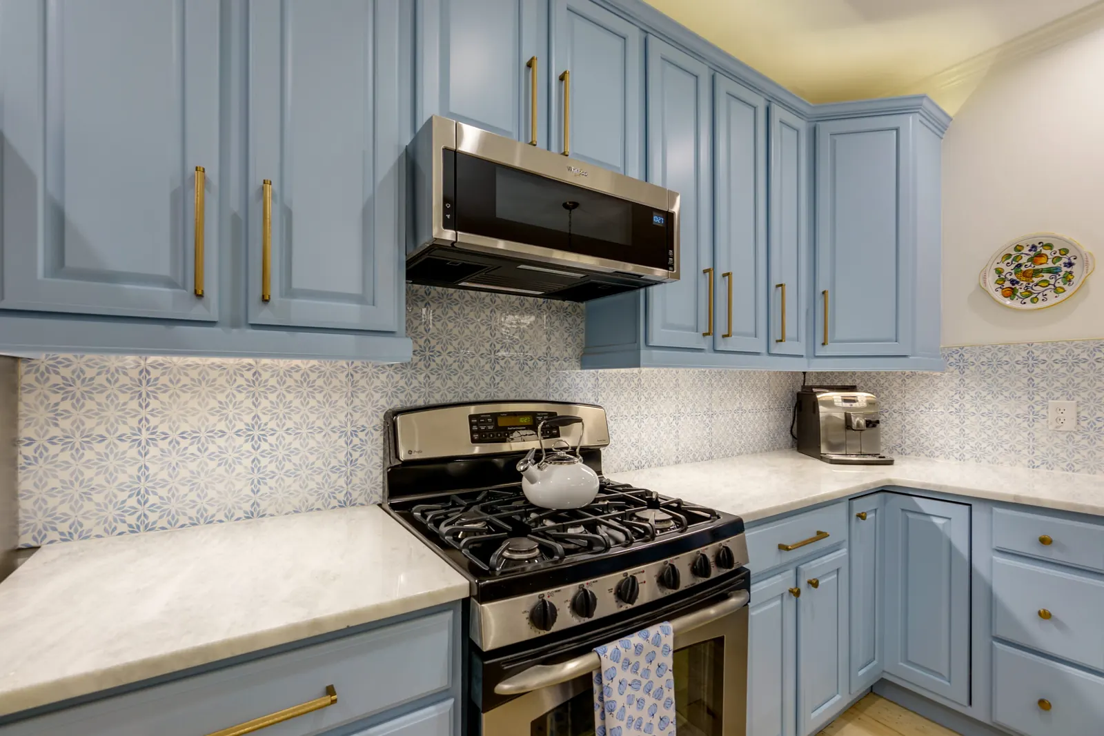 Kitchen cabinets refinished in blue-gray with brass pulls and patterned tile backsplash