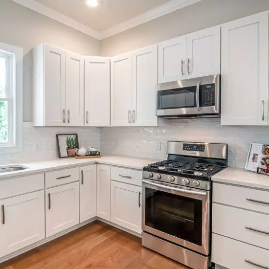 Corner kitchen with white shaker cabinets refinished, stainless gas range and microwave