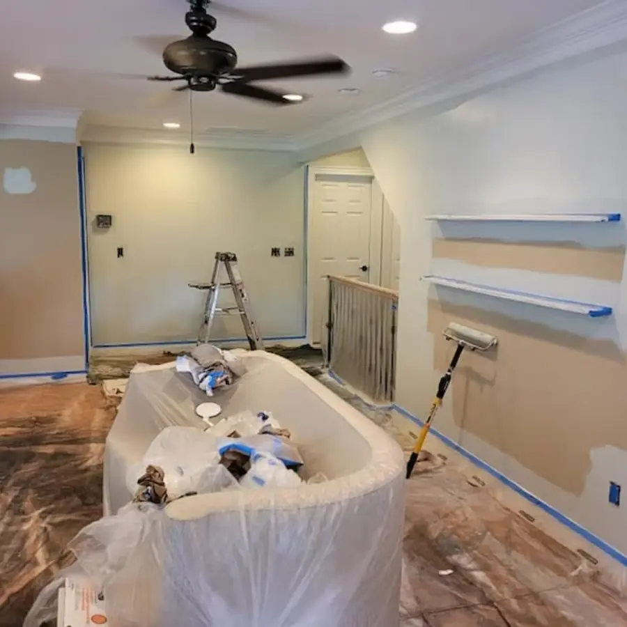 Room in progress showing blue painter's tape masking trim, windows and shelving before paint