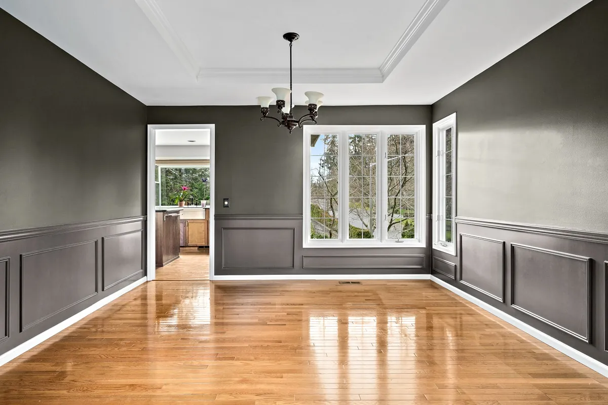Empty dining room with charcoal gray walls, white wainscoting panels and crown molding repainted