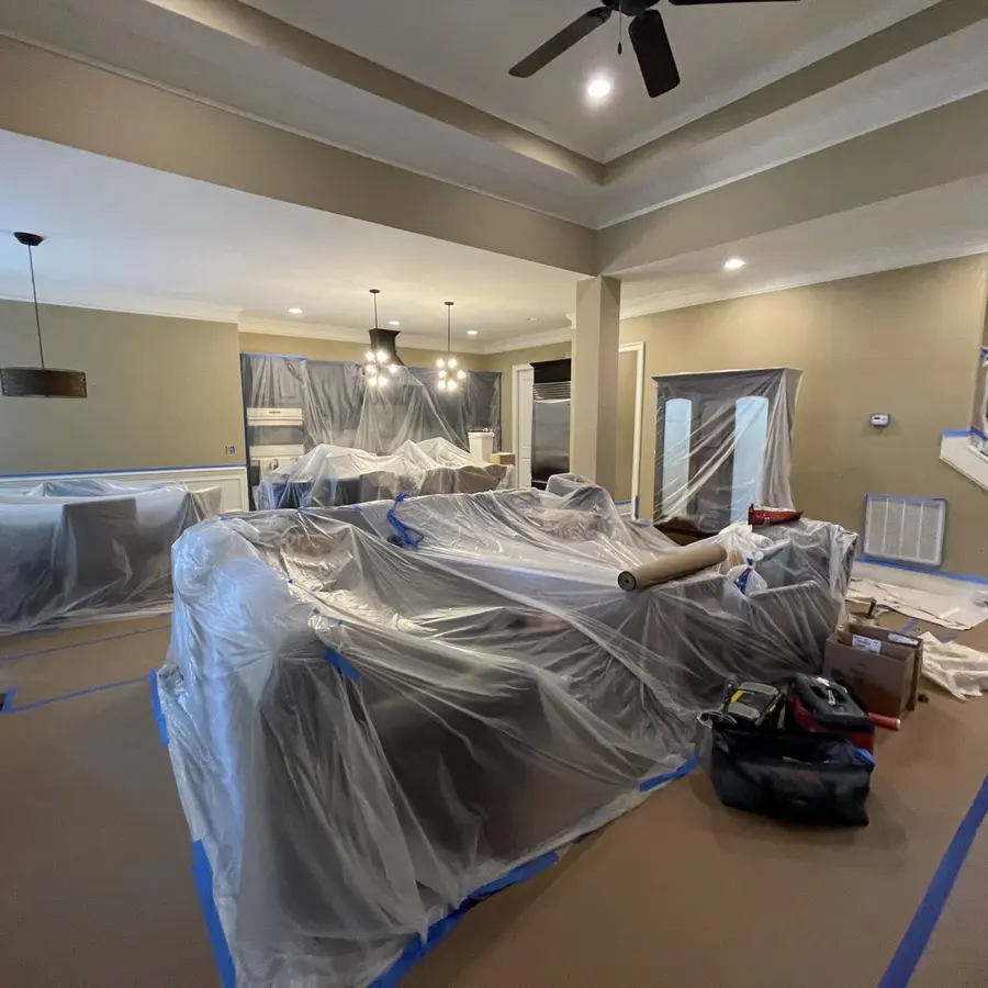 Large open plan home with all furniture wrapped in plastic and floors taped before painting