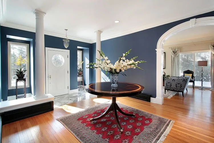 Foyer with navy blue walls, white columns and trim repainted, hardwood floors