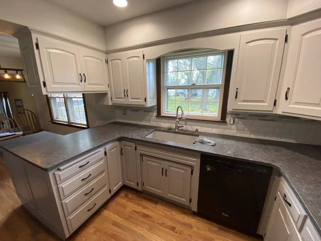 Kitchen with white cathedral-style cabinet doors, gray countertop